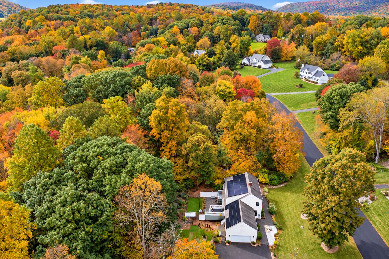Aerial view of the home surrounded by autumn woodland and rolling hills