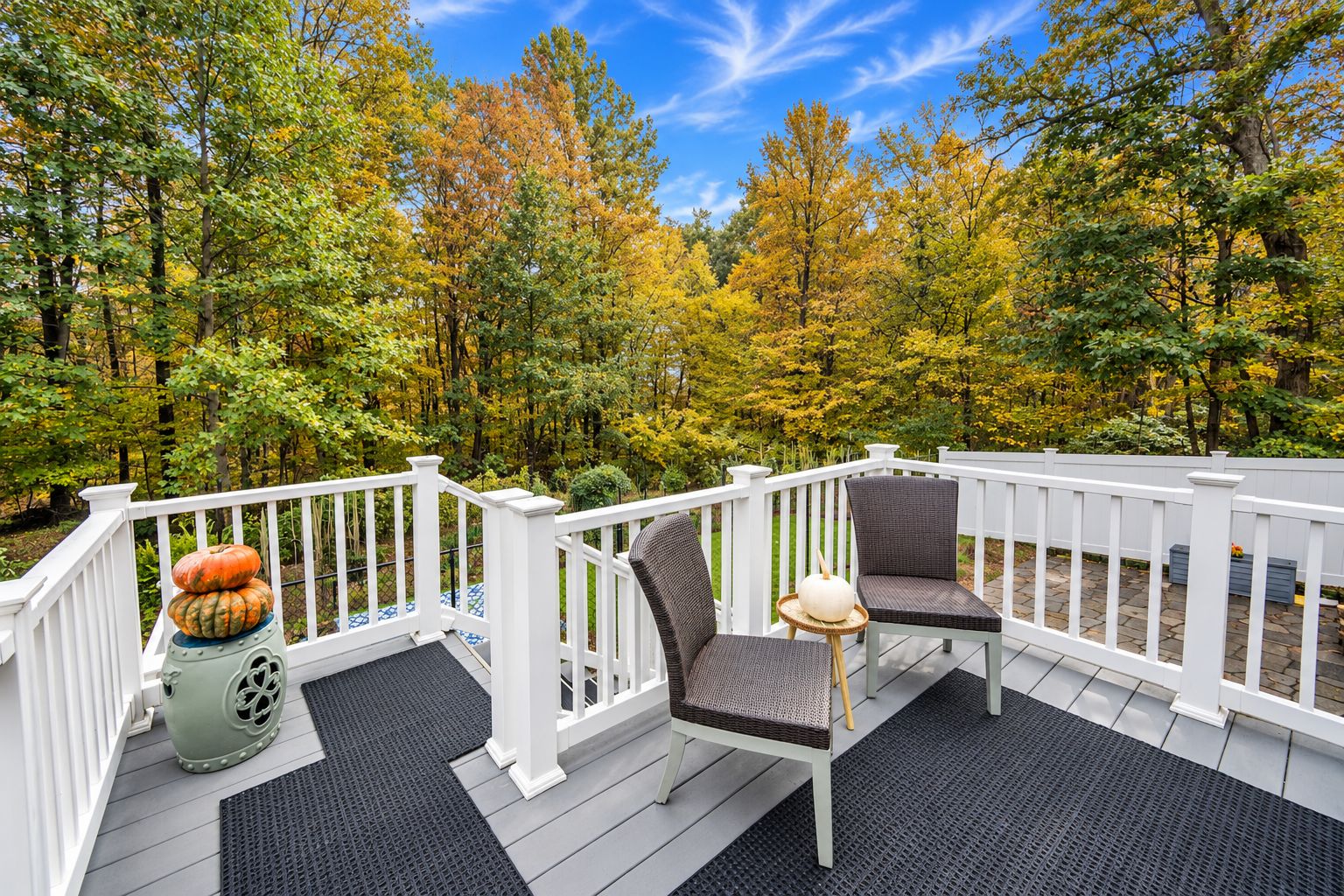 Upper deck with two chairs and pumpkins overlooking autumn trees