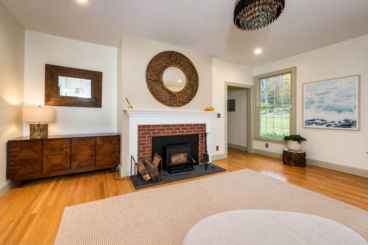 Family room with brick fireplace and wood-burning insert, hardwood floors and a window to the yard